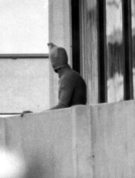 Here, a masked Palestinian terrorist looks over the balcony of the Israeli...
