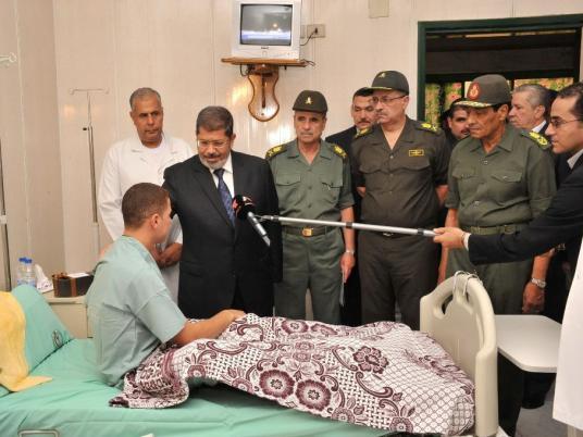 Egypt's President Mohamed Mursi (2nd L) speaks with an Egyptian soldier, whom was injured when gunmen attacked a border station between Egypt and Israel, as Egypt's military head Field Marshal Hussein Tantawi (R) looks on at a hospital in Cairo August 7, 2012. Egypt began work to seal off smuggling tunnels into the Gaza Strip on Tuesday, a security source said, two days after gunmen shot dead 16 Egyptian border guards in an attack blamed partly on Palestinian jihadi militants.