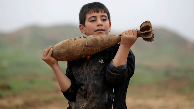 Child holds mortar in Idlib, Syria (Photo: Reuters)