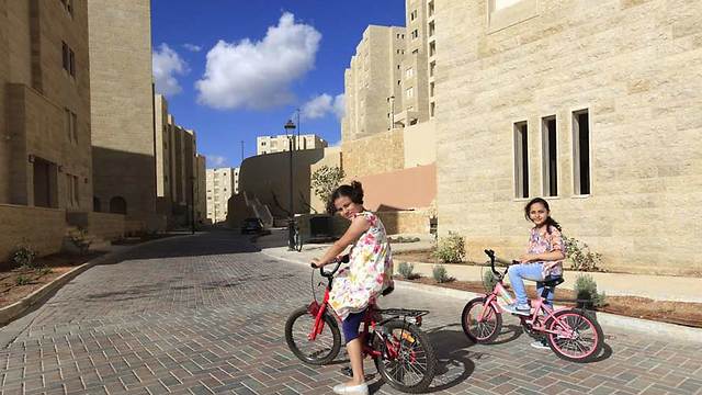 Bahee, 8, and Layan,10, bicycle in front of new apartment in Rawabi (Photo: Eloise Bollack/The Media Line)