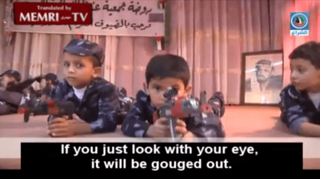 Palestinian pre-schoolers perform with toy guns at a West Bank kindergarten, June 2015. A photograph of Yasser Arafat is at the back of the stage. (MEMRI screenshot)