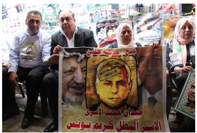 Ibrahim Ramadan, governor of the Jenin district, next to the mother of terrorist Karim Yunes at the inauguration of the "Karim Yunes square" in Jenin . They hold a sign of Karim Yunes flanked on the left by Yasser Arafat and the right by Mahmoud Abbas. The Arabic reads, "Fatah/Jenin. Detained since January 6, 1983. The square [named for] the oldest prisoner. Prisoners and hero, Karim Yunes" (bukra.net, May 18, 2017). 