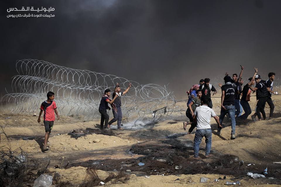 Young Gazan rioters pull at a coil of barbed wire near the security fence in eastern Khan Yunis. 