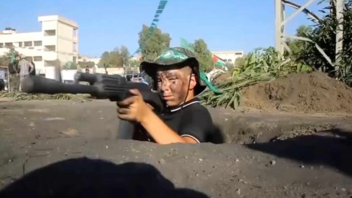 A child wields a machine gun in a clip from 'UNRWA at War'. Screenshot.